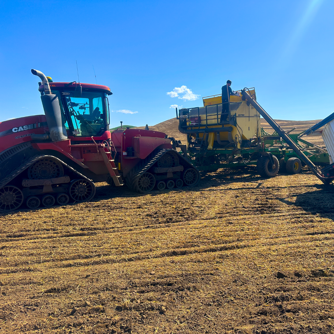 Red tractor whose seed box is being filled
